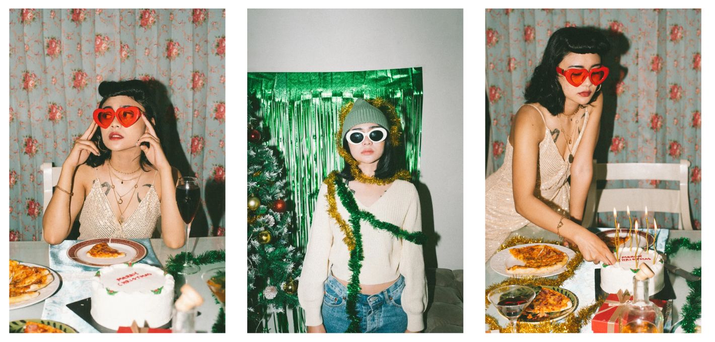Frau lacht mit Pizza und Kuchen am Tisch und feiert Anti-Weihnachten, Weihnachten allein ohne Familie