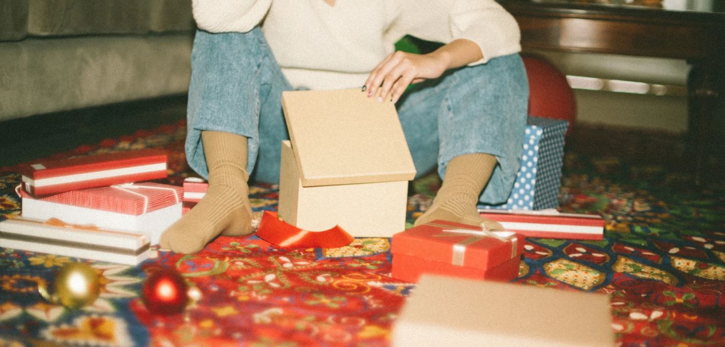 Füße in Socken zwischen Geschenken auf dem Teppich an Weihnachten allein ohne Familie